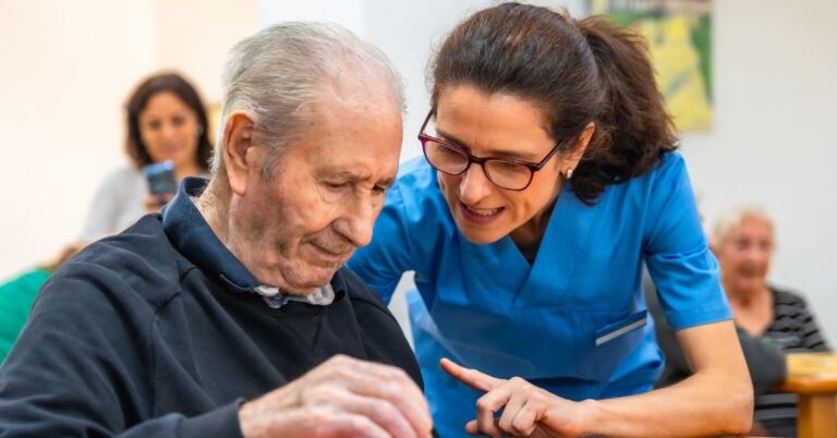 a caregiver helping a senior man in memory care program